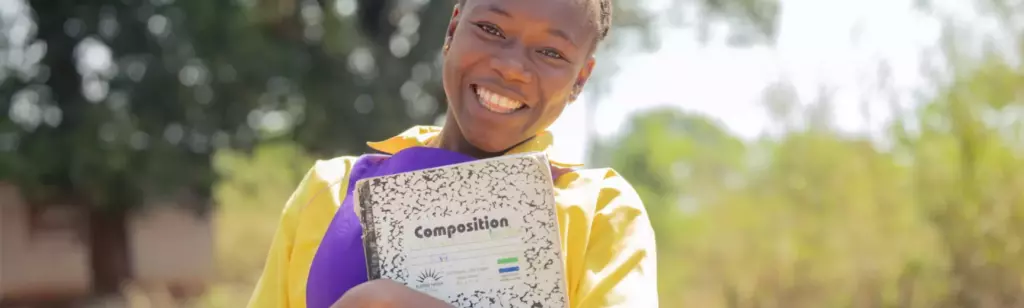Student holding school book, ESRGBV Sierra Leone